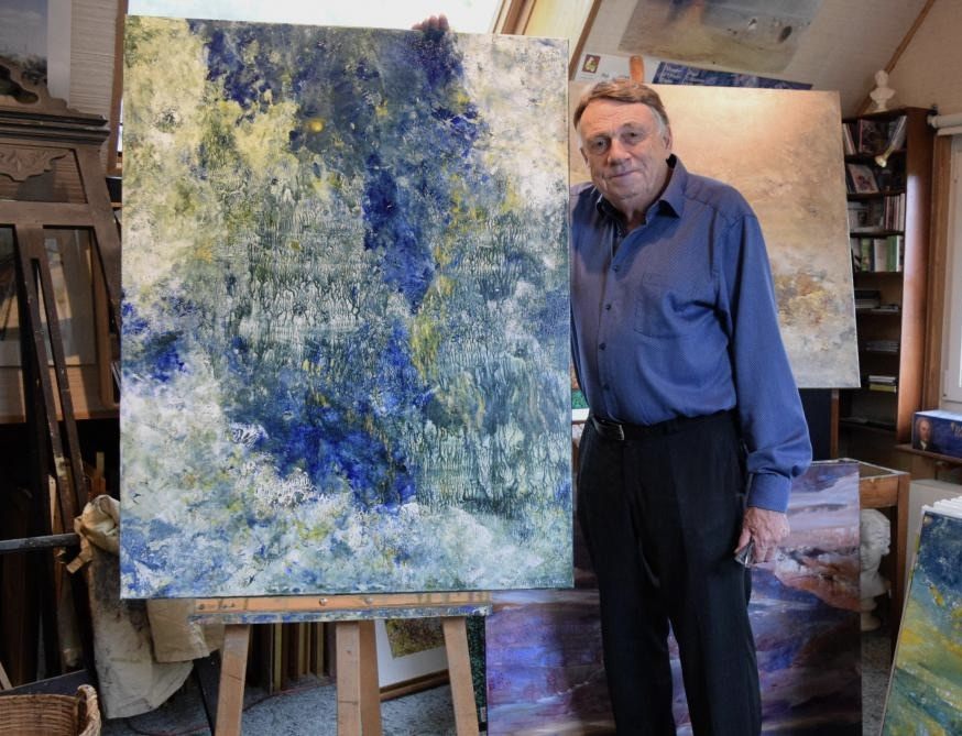 Patrick Adam dans son atelier, devant une grande toile bleue
